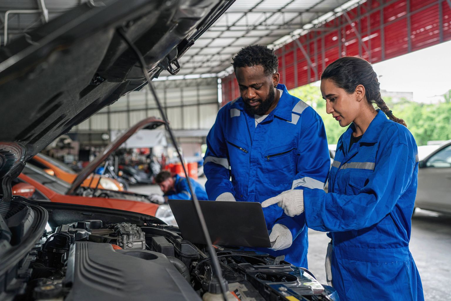 Two Sternhaus technicians reviewing live diagnostic data on a laptop under a vehicle's open hood